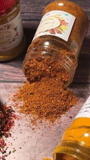 فلفل أحمر مجروش وكركم منسكب من عبوات درة على خشب